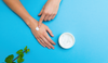 woman-applying-white-moisturizer-on-her-hands-with